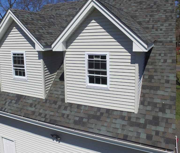 Storm-damaged roof shingles in Colorado Springs showing hail and wind impact